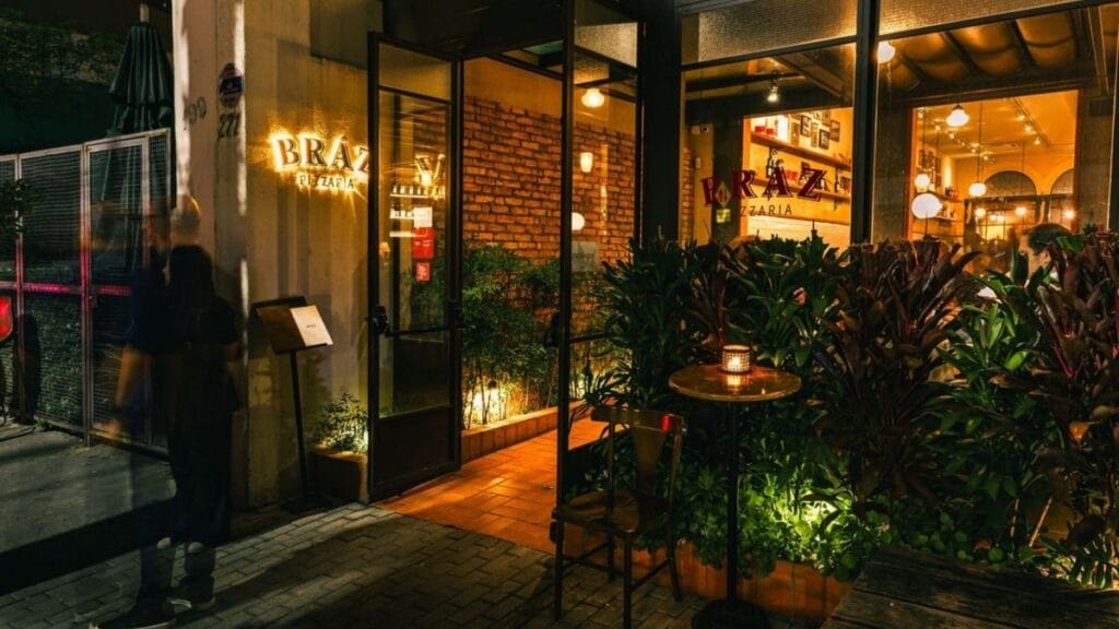 Fachada Da Bráz Pizzaria Com Iluminação Noturna, Plantas E Ambiente Aconchegante